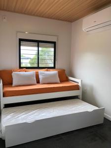 ein orangefarbenes Bett in einem weißen Zimmer mit Fenster in der Unterkunft La Sifrina Punta Negra in Punta Colorada