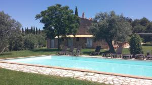 a swimming pool with chairs and a house at Azienda Agrituristica Le Chiuse in Manciano