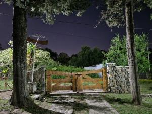 een houten poort met een stenen muur en bomen bij El Remanso Estadia Minima 2 Noches in Cordoba