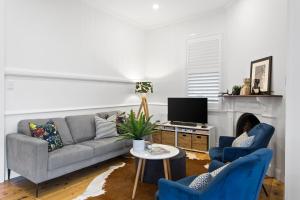 een woonkamer met een bank en 2 blauwe stoelen bij Sierra Cottage - A Homely Space, Superb Location in Toowoomba