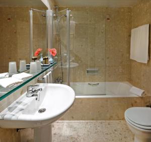 a bathroom with a sink and a tub and a toilet at Algarve Casino Hotel in Portimão