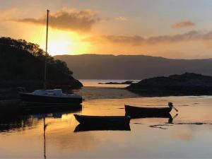 two boats sitting on the beach at sunset at Duirinish Pods with Private Hot Tubs and Duirinish Bothy with No Hot Tub in Plockton