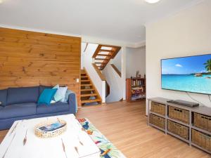 a living room with a blue couch and a large screen tv at LingaLonga in Hawks Nest