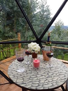 RESERVA CATEDRAL Glamping في زيباكويرا: طاولة مع ثلاثة أكواب من النبيذ وشمعة