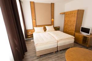 a small bedroom with a bed and a television at Altstadthotel PIAZZA in Dinkelsbühl