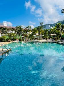 a large swimming pool at a resort with palm trees at Phuket Golden Sand Inn - SHA Extra Plus in Karon Beach