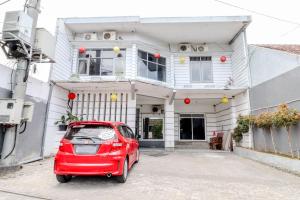 a small red car parked in front of a house at Hotel Bintang in Malang