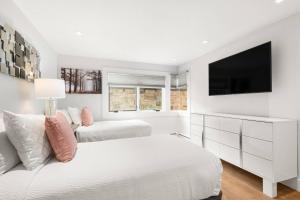 a white bedroom with two beds and a flat screen tv at 700 Monarch 104 in Aspen
