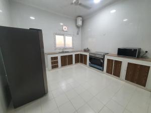 a kitchen with a black refrigerator and a white tile floor at شاليه الشهد in Ma‘ābīlah