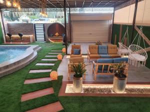 sala de estar con piscina, sofá y sillas en شاليه الشهد, en Ma‘ābīlah