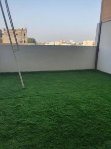 Zimmer mit grünem Gras und einer weißen Wand in der Unterkunft شاليه الشهد in Ma‘ābīlah