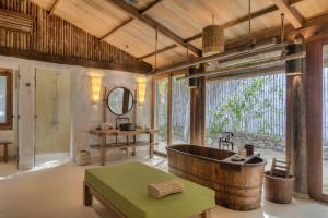 La salle de bains est pourvue d'une baignoire en bois et d'une table. dans l'établissement Six Senses Ninh Van Bay, à Baie de Ninh Van
