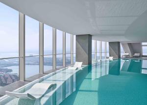 uma piscina com cadeiras brancas num edifício em Niccolo Suzhou em Suzhou