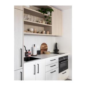 uma cozinha com armários brancos e electrodomésticos pretos em Studio On Park em Albion Park