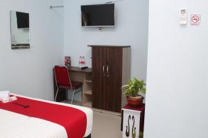 Schlafzimmer mit einem Bett und einem Schreibtisch mit einem TV in der Unterkunft RedDoorz Syariah near Suncity Mall Madiun in Madiun