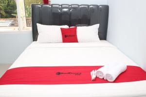 a bed with a red and white blanket and two towels at RedDoorz Syariah near Suncity Mall Madiun in Madiun