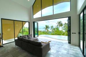 un soggiorno con divano e ampie finestre di Villa Oikos a Chaweng Noi Beach