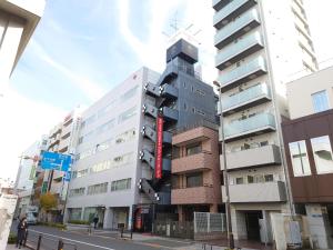 een hoog gebouw met een rood bord aan de zijkant bij Spa&Capsule Hotel Grandpark Inn Kitasenju in Tokyo