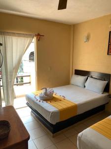 a bedroom with two beds and a large window at HOTEL MARIPOSA in Zihuatanejo