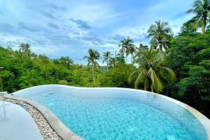 a swimming pool with trees in the background at Villa Lola in Chaweng Noi Beach