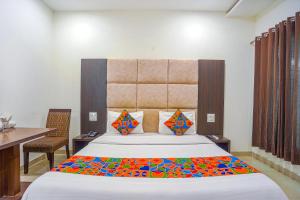 a bedroom with a large bed and a desk and a table at FabHotel Grand Inn in Jalandhar
