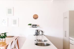 a white kitchen with a sink and a table at The Villa Margaret River in Margaret River Town