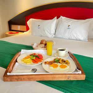 a tray with two plates of food on a bed at Hotel Costa Azul in Acapulco