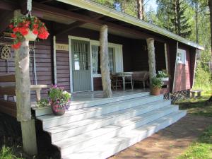 a porch of a wooden cabin with flowers on it at Jokiniemen Matkailu Cottages in Tölvä