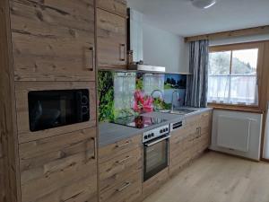 a kitchen with wooden cabinets and a sink and a microwave at Bauernhof - Appartement beim Zefferer in Schladming