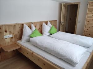 a bed with green and white pillows on it at Bauernhof - Appartement beim Zefferer in Schladming