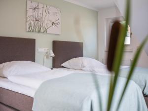 een slaapkamer met een bed met witte lakens en kussens bij Feriendomizil im Luftkurort - Ferienhaus-Sauna-See -Entertainmentpaket in Krakow am See