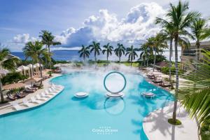 einen Pool in einem Resort mit Palmen und einem Spiegel in der Unterkunft Coral Ocean Resort in Saipan