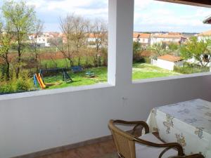 ein Esszimmer mit einem Tisch und 2 Fenstern in der Unterkunft Apartments Cerin in Fažana