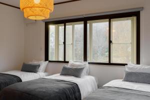 3 camas en una habitación con ventanas y lámpara de araña en SOTO Myoko - close to Akakura Onsen Ski Lift and Town en Myoko