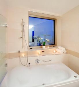 a bathroom with a tub, sink, mirror, and bathtub at Hotel Aristos in Zagreb