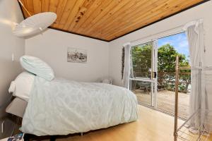 a bedroom with a bed and a large window at Bach and Relax - Oakura Holiday Home in Whangaruru North