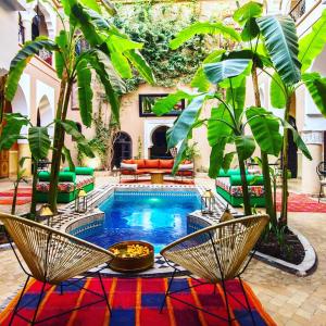 a courtyard with a pool with chairs and trees at Riad Nabila in Marrakesh