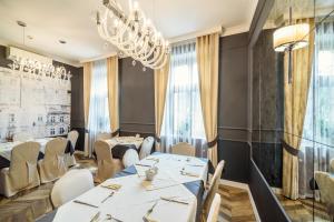 カリシュにあるHotel Europaの白いテーブルと椅子、シャンデリアのあるレストラン