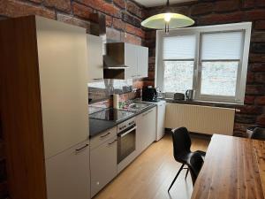 a kitchen with white cabinets and a brick wall at Cottbuser City Ferienwohnung in Cottbus