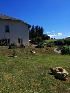 une cour avec une maison et un rocher dans l'herbe dans l'établissement Pont de la Chaux 2, à Chaux-des-Crotenay