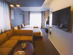 um quarto de hotel com um sofá e uma cama em GRAND BASE Hakata Bay em Fukuoka