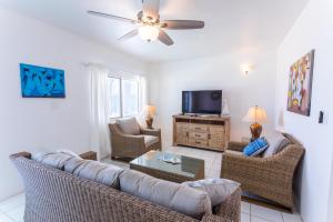 a living room with a couch and chairs and a tv at Coralito Bay Suites & Villas in The Valley