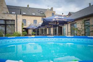 a swimming pool in front of a building with umbrellas at Oud Gemeentehuis in Poelkapelle