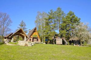 Rustic cottage JARILO, an oasis of peace in nature في Ležimir: منزل خشبي كبير على رأس ميدان أخضر