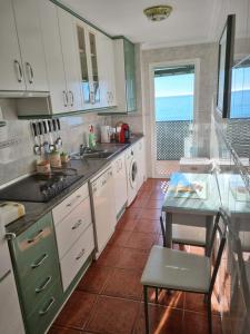 una cucina con mobili bianchi, un tavolo e una finestra di Vistamar Estepona a Estepona Altre 5 foto