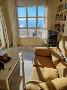 un soggiorno con un divano, un tavolo e una finestra di Vistamar Estepona a Estepona