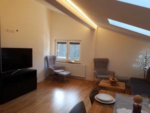 a living room with a flat screen tv and chairs at Ferienwohnung Rainer in Fieberbrunn