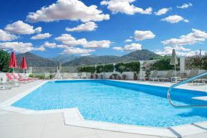 a pool with chairs and umbrellas in a resort at Hiona Holiday Hotel in Palekastron