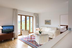 a white living room with a couch and a tv at Ferienwohnungen am Walmendingerhorn in Mittelberg