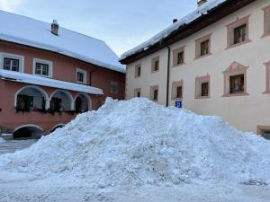 een berg sneeuw voor twee gebouwen bij Chasa Engadina in Sent